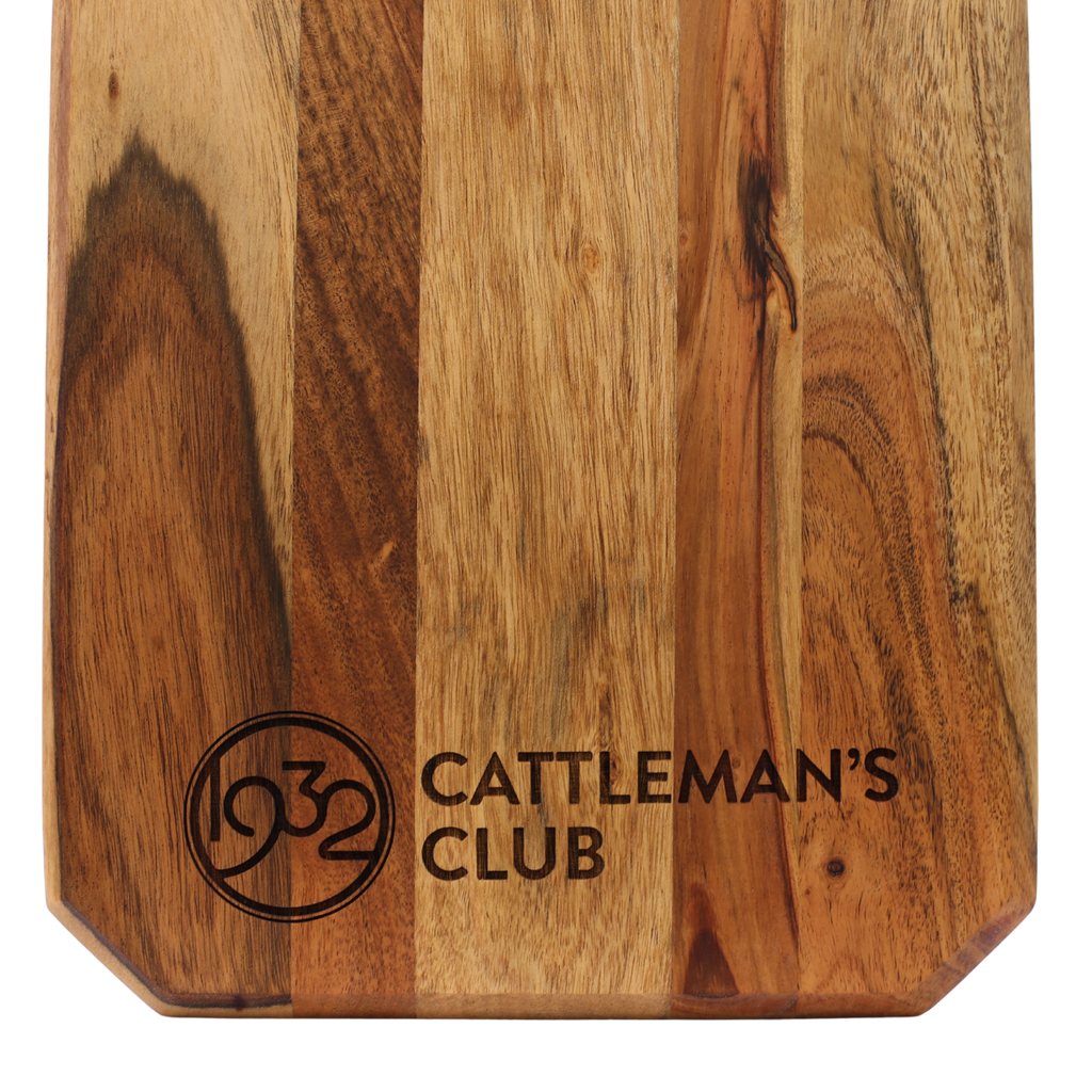 Wooden cutting board with 'Cattleman's Club' logo and text on a white background