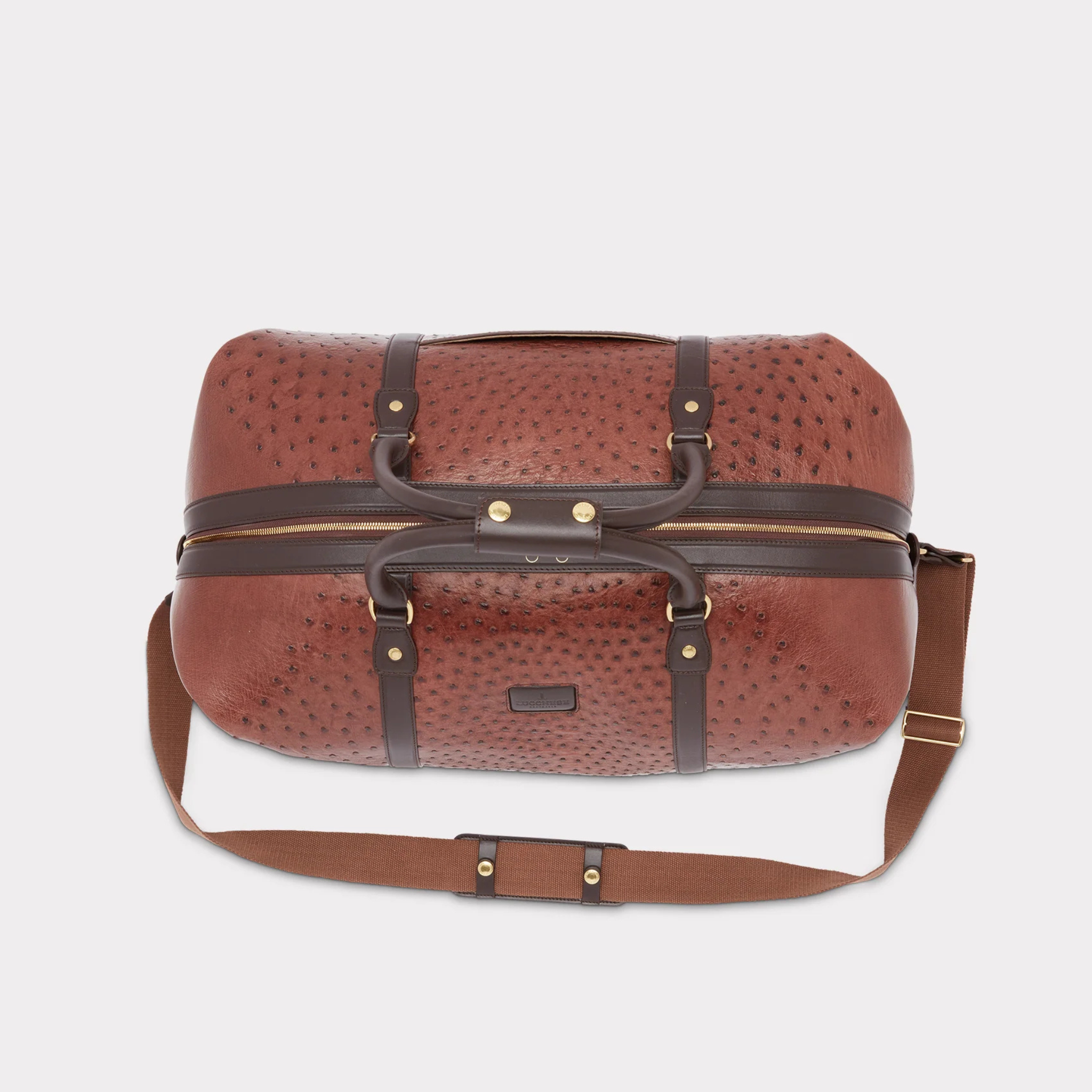 Over view of a Brown textured duffel bag with straps and gold accents on a light gray background