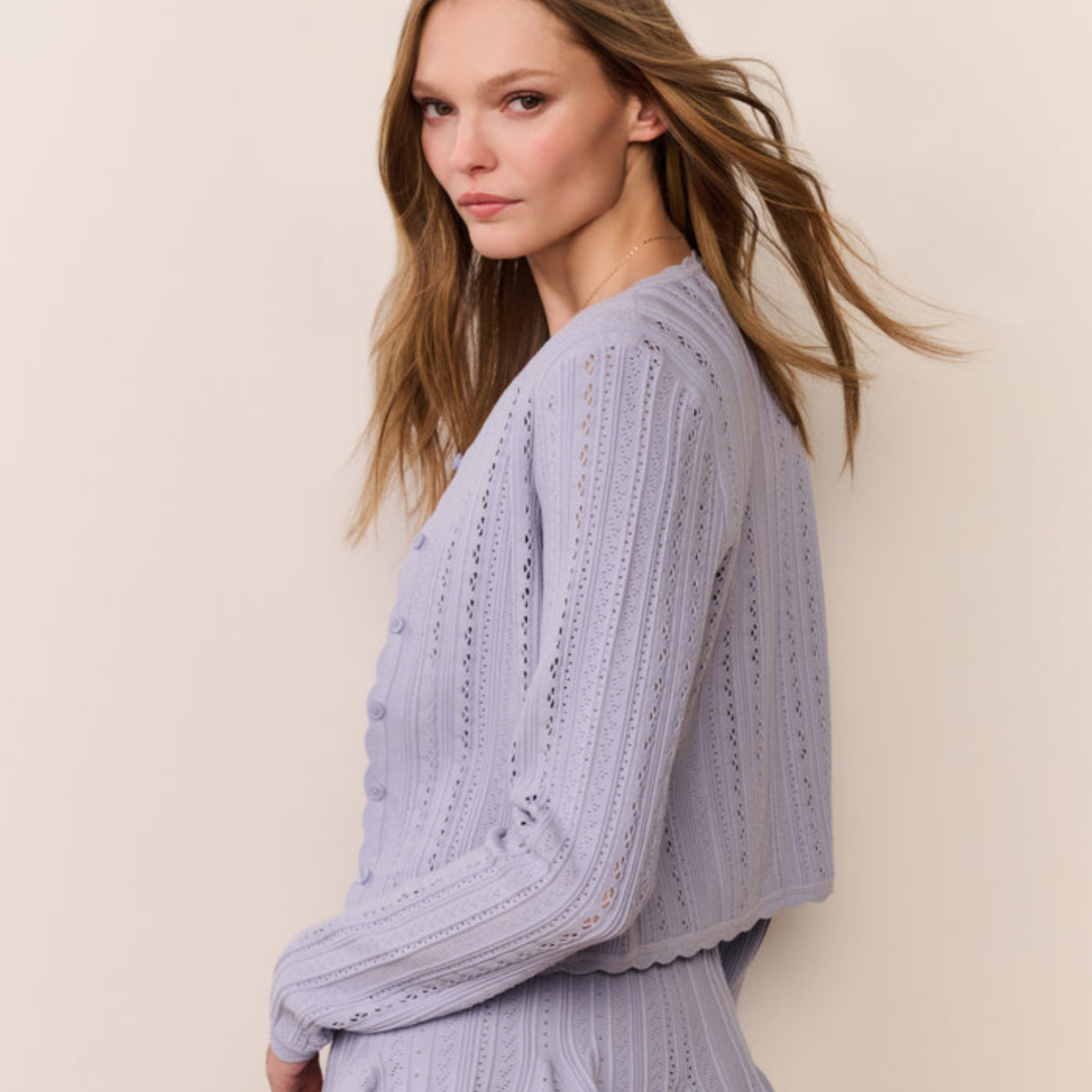 Side view of a Woman wearing a light blue sweater against a beige background
