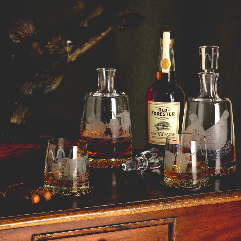 Old Forester bourbon bottle with glasses and decanter on a wooden surface