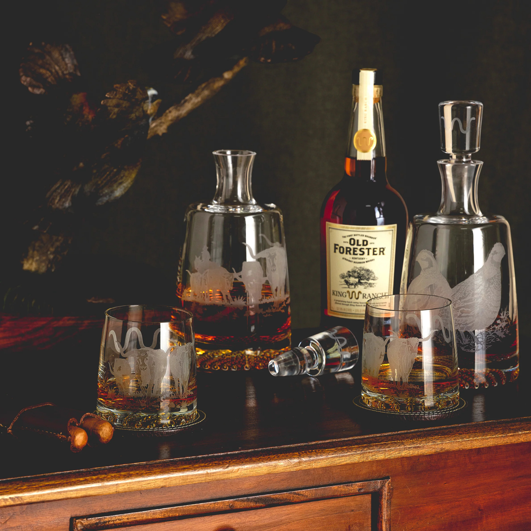 Old Forester bourbon bottle with glasses and decanter on a wooden surface