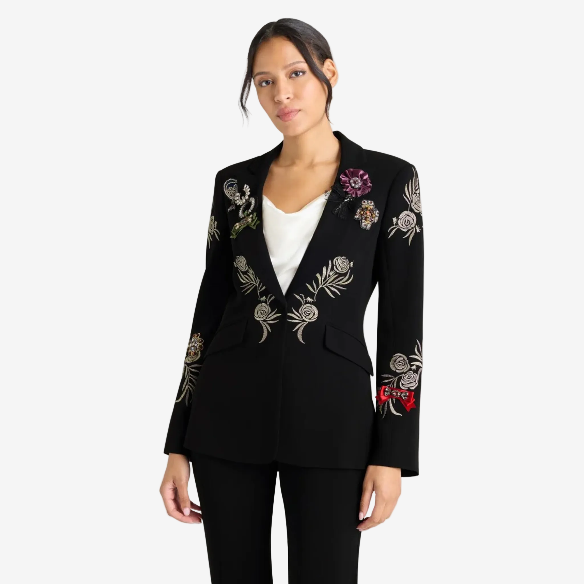 Black tailored blazer adorned with floral and jeweled appliqué details on the shoulders, lapel, sleeves, and torso, worn over a white satin camisole and paired with matching black trousers.