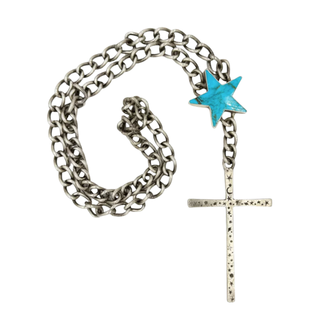 A silver chain necklace featuring a large turquoise star accent and a long silver cross pendant engraved with small stars and crescent moon shapes.