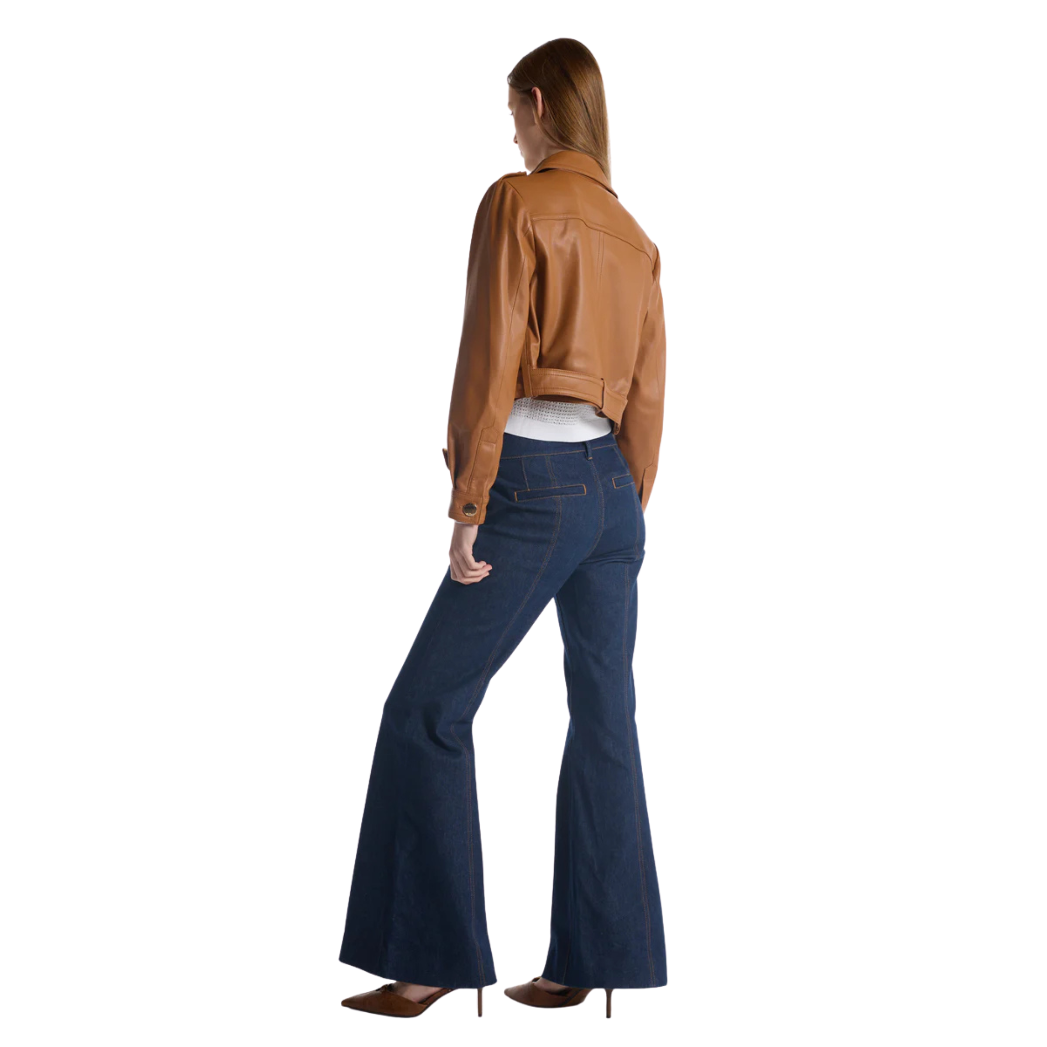 Model wearing a cropped tan leather jacket with front flap pockets and a belted waist, paired with a white textured top, dark wide‑leg denim pants, and pointed‑toe heels.