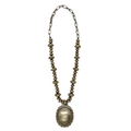 A long silver necklace featuring flattened oval beads along the lower portion and elongated chain links at the top, finished with a large oval pendant edged in a scalloped, engraved border.